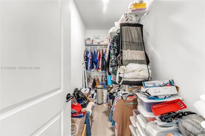 Walk-in closet featuring light-toned wood-finish flooring and tiered wire shelving
