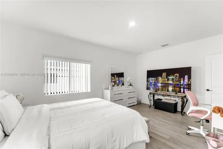 Neutral interior featuring wood-finish flooring, recessed lighting, and a single-panel interior door