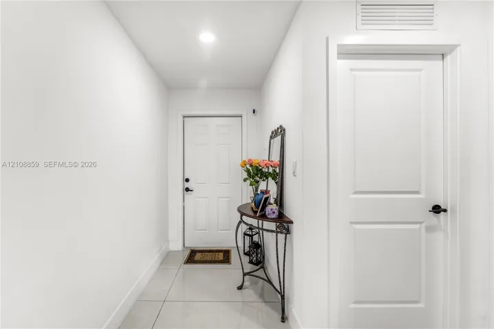 Entryway featuring large-format ceramic tile flooring, recessed lighting, and a six-panel front door with matte black hardware