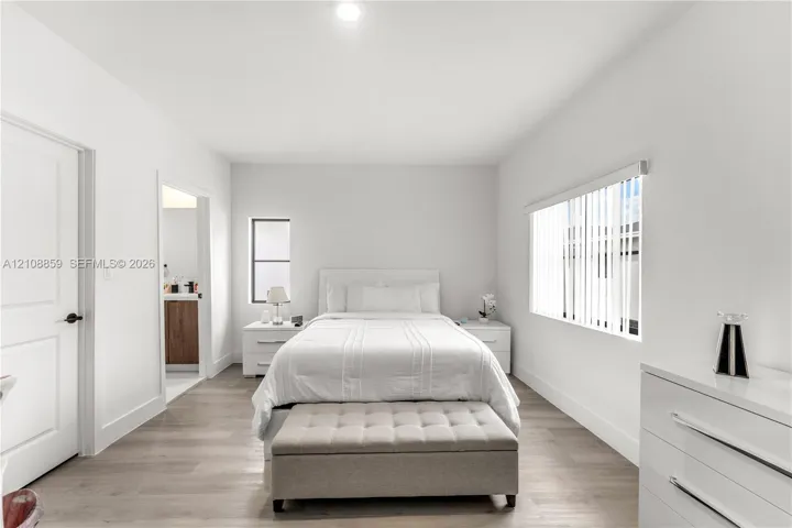 Neutral-toned wood-finish flooring, recessed ceiling lighting, and vertical window blinds