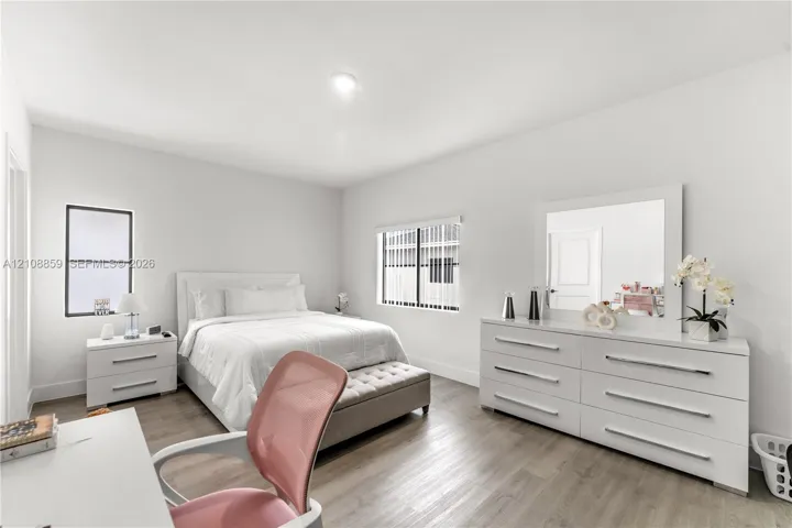 Neutral interior space featuring wood-finish flooring, crisp white walls, dual windows, and recessed ceiling lighting