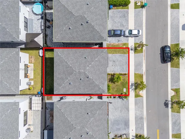 Aerial perspective of property lot featuring a hip roof, paved driveway, and established lawn