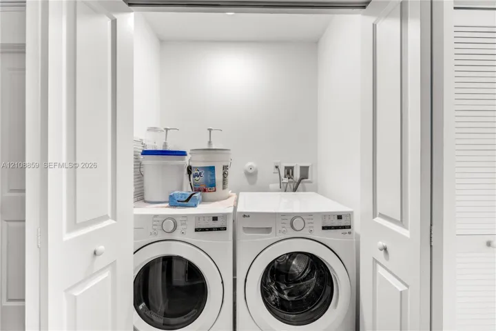 Laundry closet featuring louvered bi-fold doors, white interior finishes, and dedicated utility hookups