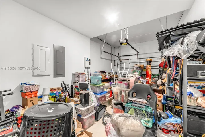 Enclosed garage space featuring an overhead automatic door opener, dual electrical service panels, and a tankless water heater