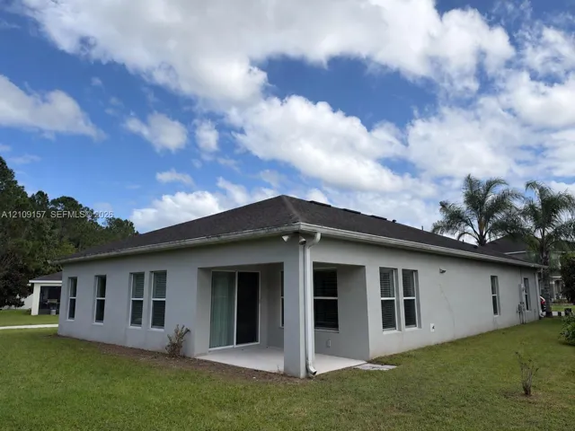 Stucco exterior featuring a hipped roof, covered patio, sliding glass door, and multiple window configurations