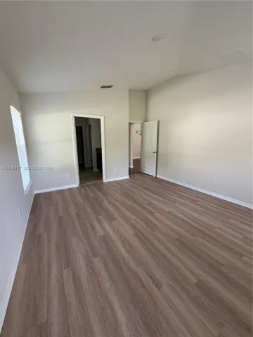 Neutral interior space featuring wood-finish flooring, vaulted ceilings, and multi-panel interior doors