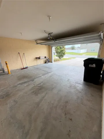 Enclosed garage featuring concrete flooring, masonry block walls, and an overhead automatic door opener