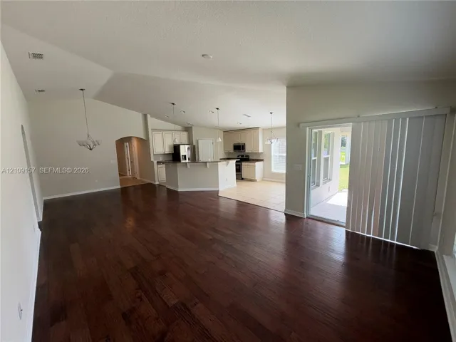 Vaulted ceilings, wood-finish flooring, kitchen featuring a peninsula island, tile flooring, and sliding glass door