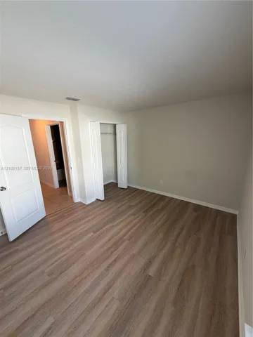 Interior room featuring wood-finish flooring, neutral wall paint, and a reach-in closet with bi-fold doors
