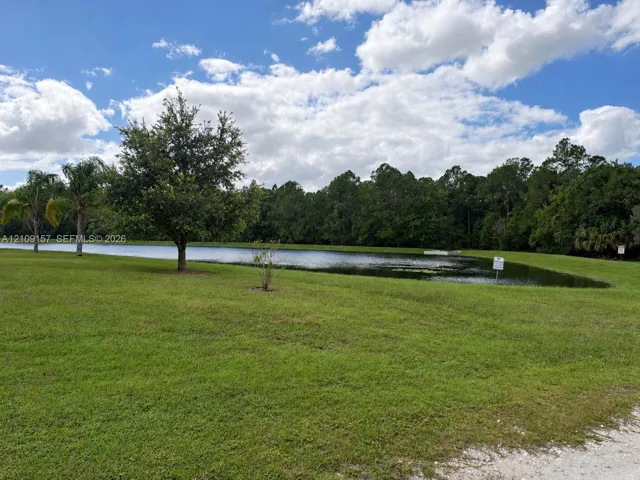 Expansive waterfront lot featuring mature trees, manicured lawn, and a natural pond