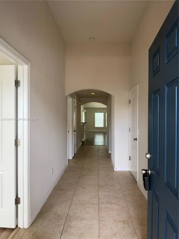 Entryway featuring a dark blue panelled door, neutral wall tones, large-format tile flooring, and arched architectural details