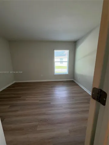 Room featuring neutral-toned walls, wood-finish flooring, and a single-pane window