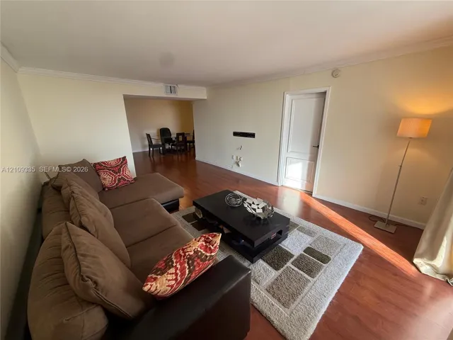Wood-finish flooring, neutral wall tones, crown molding, and a single-panel interior door