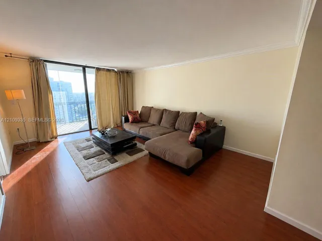 Living area featuring wood-finish flooring, crown molding, and sliding glass doors leading to an exterior balcony