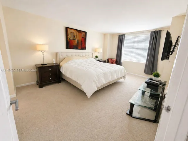 Neutral-toned interior space featuring wall-to-wall carpeting and a window with horizontal blinds