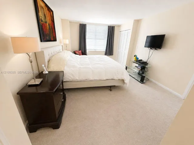 Neutral carpeting, multi-panel closet doors, and a window with horizontal blinds