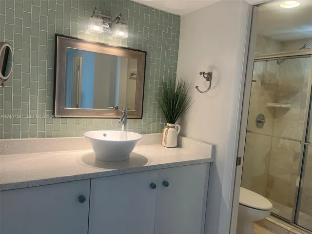 Vanity with a vessel sink, a light-colored countertop, and light-colored cabinetry