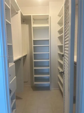 Custom closet system featuring white shelving units, integrated drawers, and hanging rods