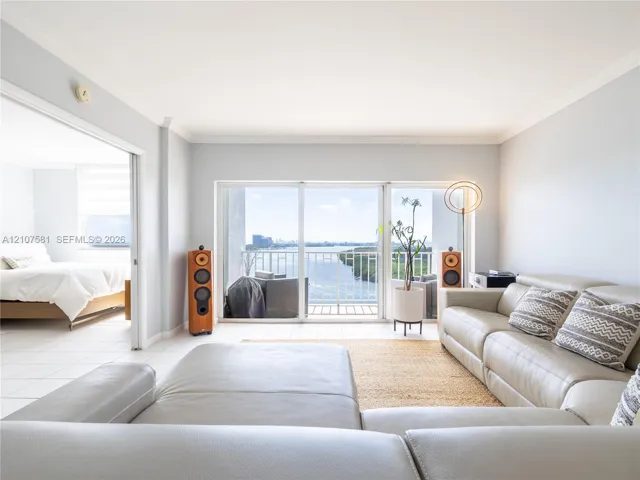 Sliding glass doors leading to a balcony, white tile flooring, and light-colored wall paint