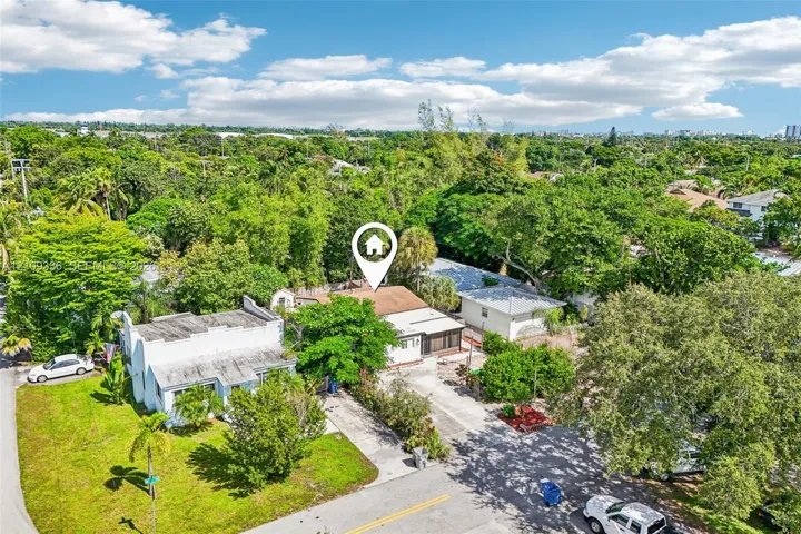 Aerial view of property featuring a shingle roof, concrete driveway, and mature landscaping
