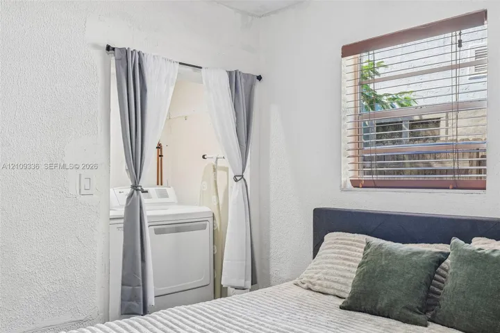 Textured walls and a recessed alcove featuring an integrated laundry hookup with washer