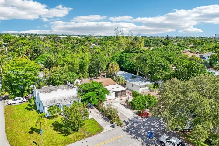 Aerial perspective of property featuring multiple structures, paved driveways, and expansive mature landscaping