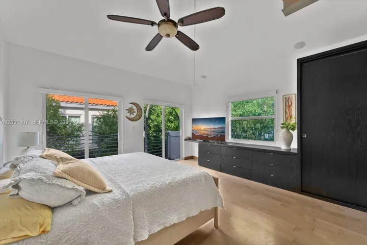 Vaulted ceilings, wood-finish flooring, built-in black cabinetry, ceiling fan, and sliding glass doors