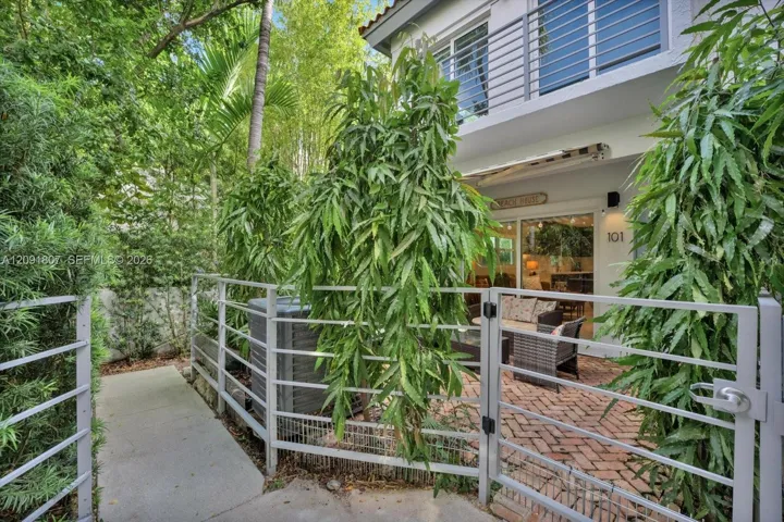 Private courtyard featuring a brick-paver patio, gated metal fencing, and mature landscaping