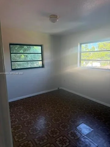 Interior room featuring neutral-toned walls, patterned tile flooring, and two horizontal slider windows