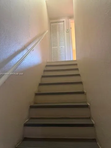 Staircase featuring painted risers and treads with a wall-mounted handrail and bi-fold closet door