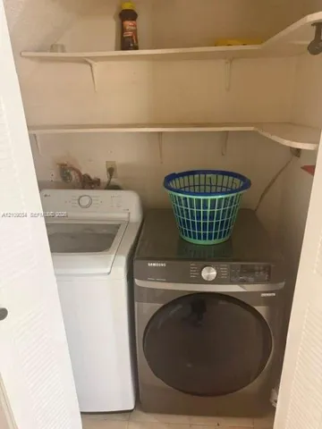 Laundry area featuring louvered bi-fold doors and two levels of built-in shelving