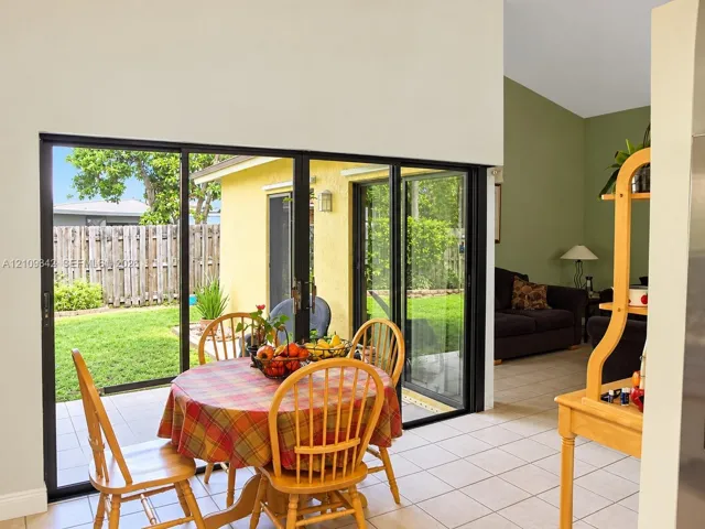 Floor-to-ceiling black-framed sliding glass doors featuring neutral tile flooring and high vaulted ceilings