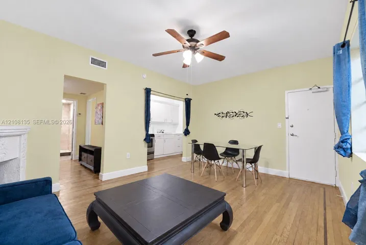 Hardwood flooring, ceiling fan with integrated lighting, and decorative fireplace mantel