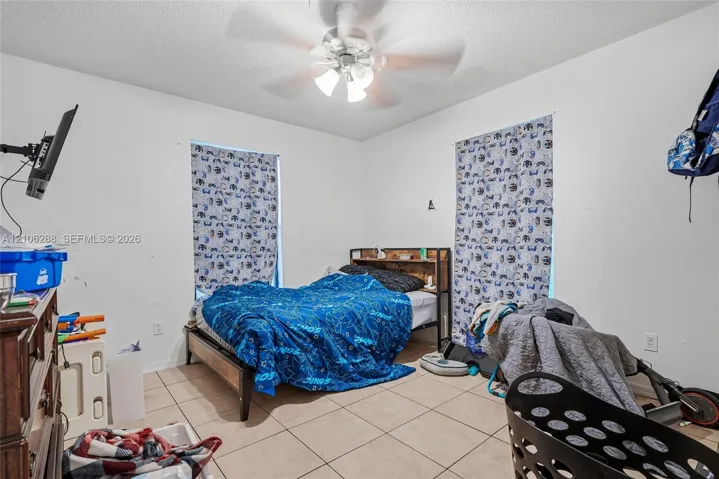 Ceramic tile flooring, multi-blade ceiling fan with integrated lighting fixture, and two windows