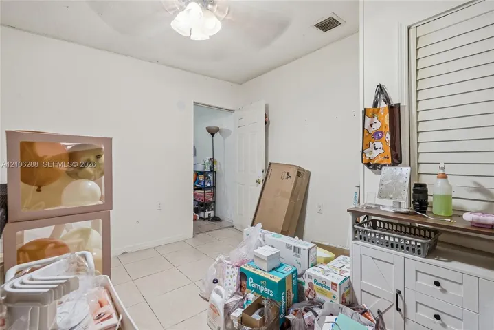 Interior room featuring neutral wall finishes, tile flooring, a multi-light ceiling fan, and horizontal louvered window shutters