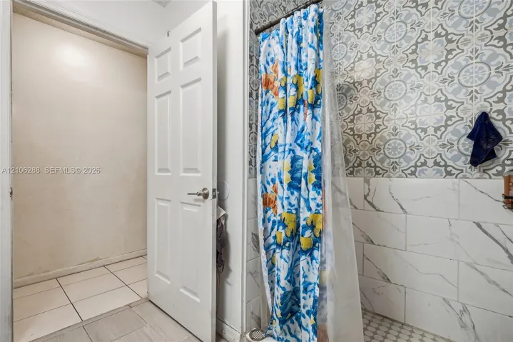 Shower surround featuring patterned tile accents, subway-style wall tile with vein detailing, and hexagonal floor tile