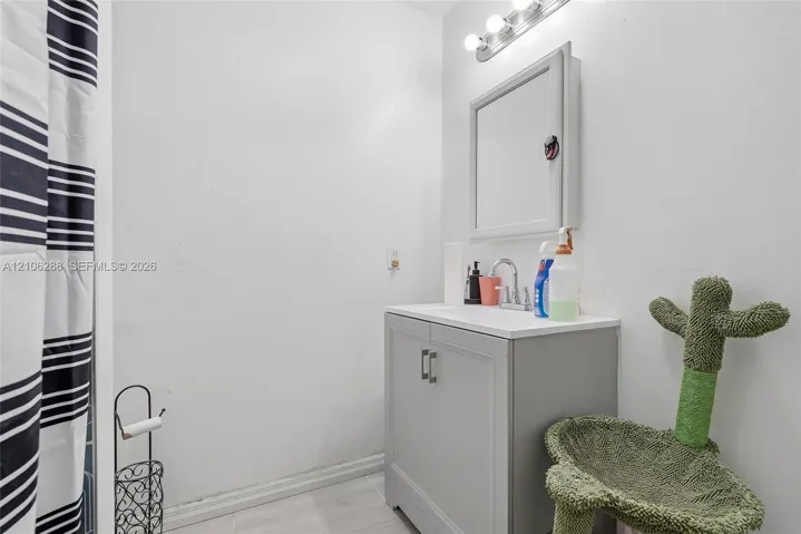 Bathroom vanity featuring a solid-surface countertop, dual-door gray cabinet, and wall-mounted medicine cabinet with a three-light fixture