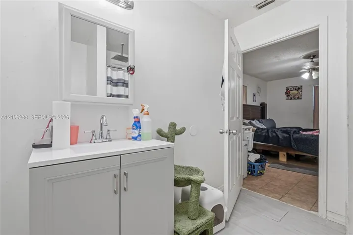 Bathroom featuring a grey vanity cabinet with a white countertop, polished chrome faucet, medicine cabinet with a mirrored door, and wall-mounted light fixture