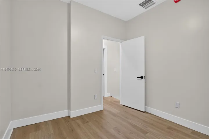 Neutral-toned walls paired with wood-finish flooring and a white interior door featuring matte black hardware