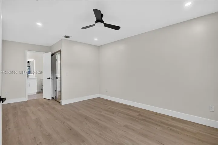 Neutral-toned interior featuring wood-finish flooring, recessed lighting, and a matte black ceiling fan
