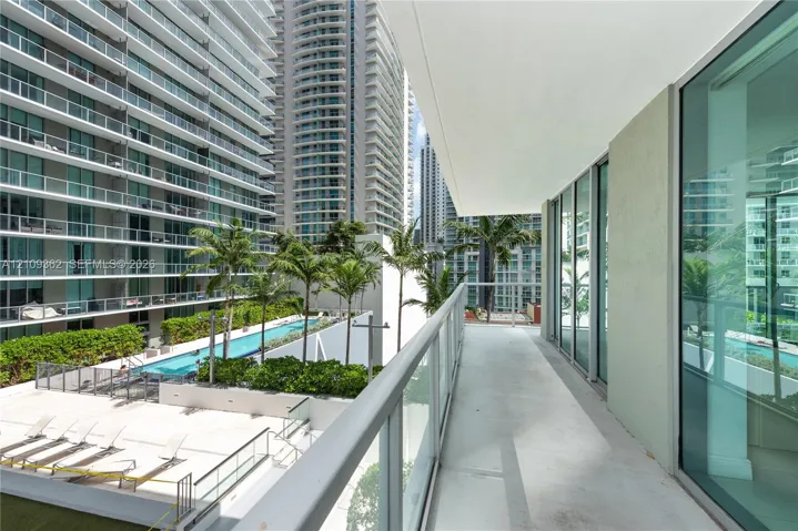 Covered balcony featuring a glass-panel railing, concrete flooring, and floor-to-ceiling glass wall