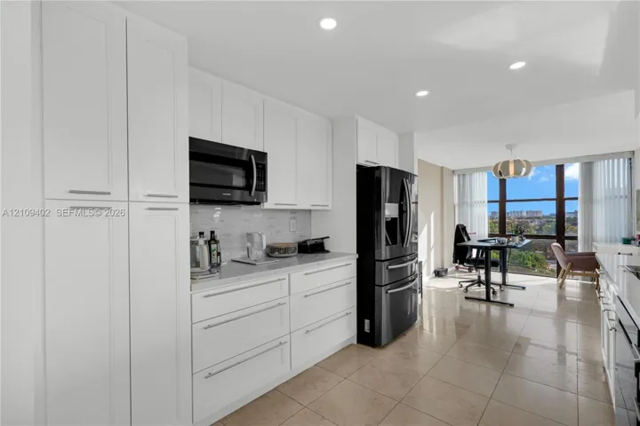 Kitchen featuring white cabinetry, stone-finish countertops, black built-in appliances, recessed lighting, and tile flooring