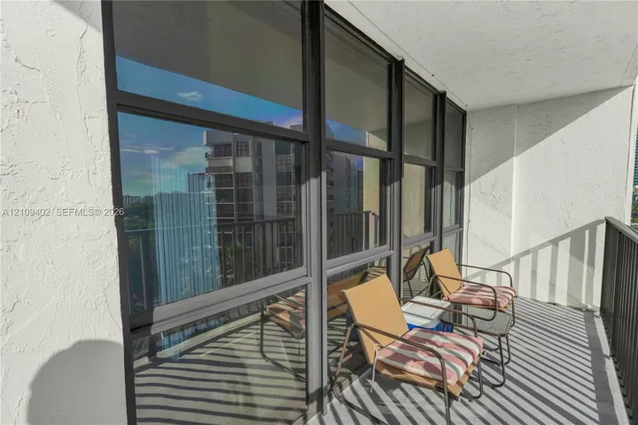 Balcony featuring full-height glass windows with dark frames, textured walls, and a metal railing