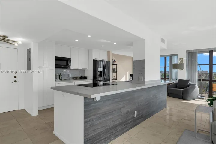 Kitchen featuring white cabinetry, quartz countertops, a stone-finish island base, recessed lighting, and tile flooring