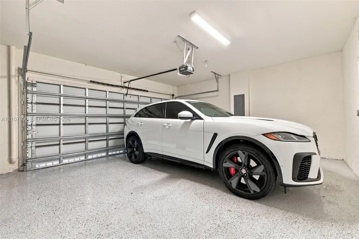 Enclosed garage featuring finished epoxy flooring, automated door mechanism, and overhead lighting