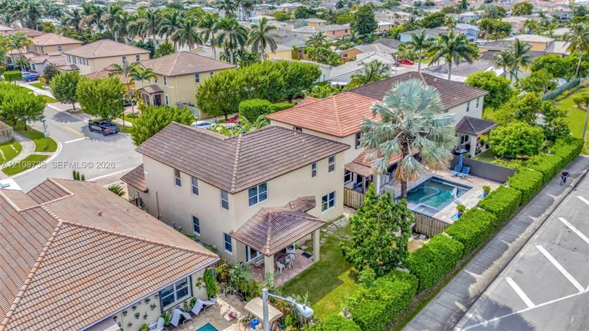 Two-story residence featuring a tile roof, an in-ground swimming pool, a paved patio, and mature landscaping