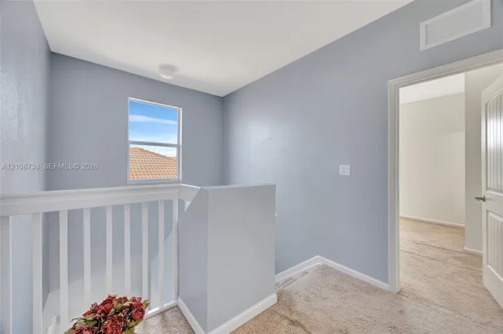 Neutral-toned interior featuring white baluster railing, wall-to-wall carpeting, and a multi-panel door