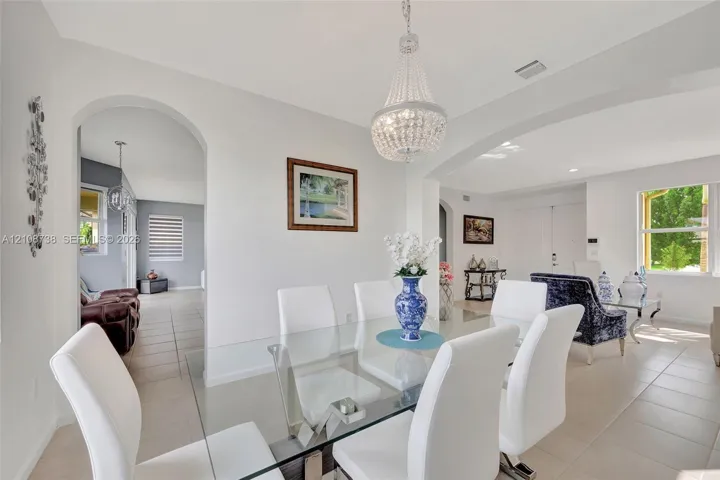 Open concept interior featuring arched wall openings, neutral tile flooring, and a crystal chandelier