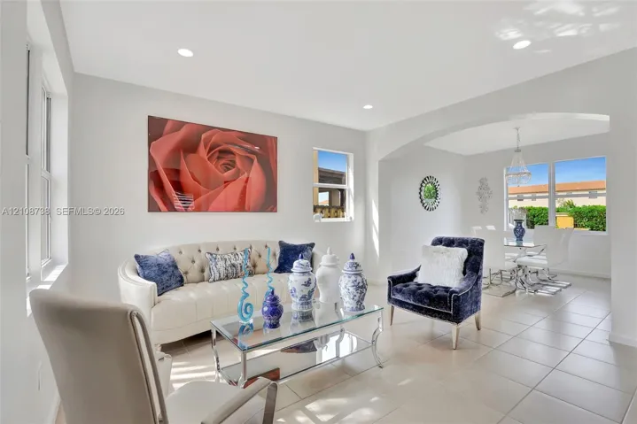 Neutral-toned tile flooring, recessed ceiling lighting, arched entryway, and large windows providing natural light