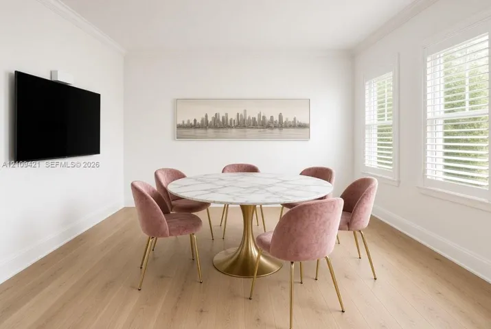 Bright room featuring wood-finish flooring, dual windows with plantation shutters, and crown molding
